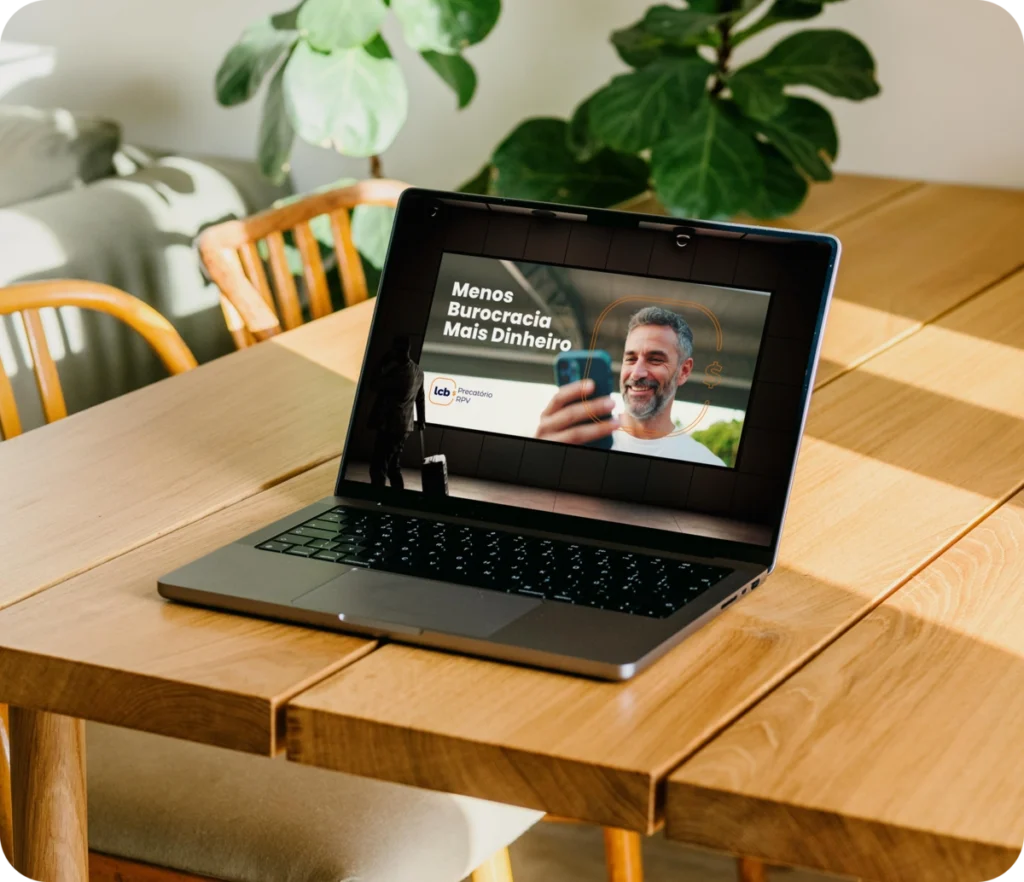 Laptop aberto exibindo vídeo "Menos Burocracia Mais Dinheiro" com homem sorrindo